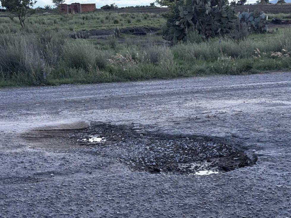 Carretera de Nopala de Villagr\u00e1n con dos baches profundos llenos de agua y pavimento roto durante la temporada de lluvias.
