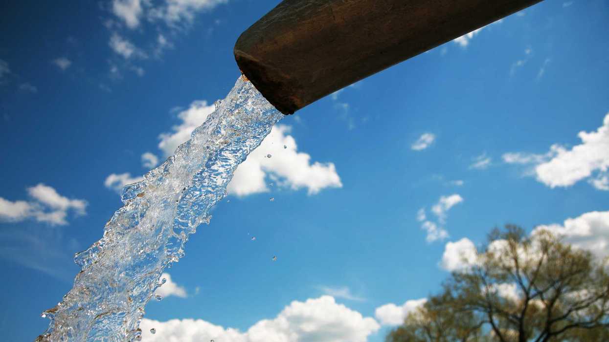Chorro de agua sale de un tubo bajo un cielo azul con nubes, imagen ilustrativa de los tandeos de agua en Guadalajara.