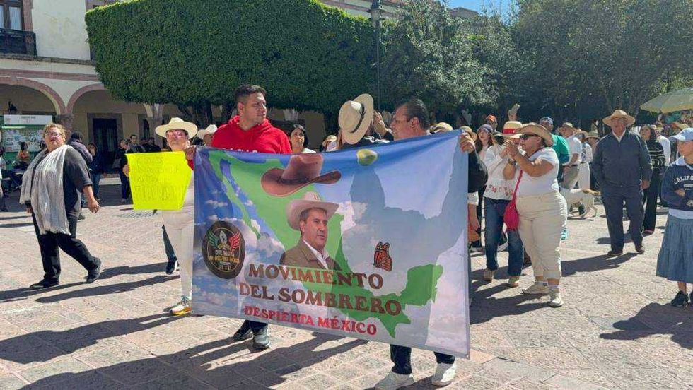 Ciudadanos reunidos en Plaza de Armas de Querétaro portando pancartas y sombreros durante manifestación por seguridad.