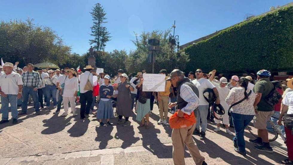Ciudadanos reunidos en Plaza de Armas de Querétaro portando pancartas y sombreros durante manifestación por seguridad.