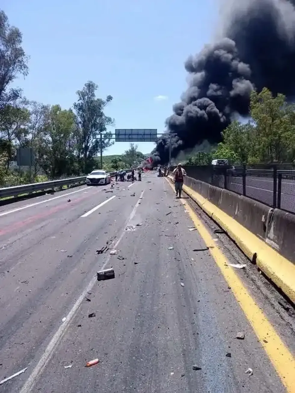 Columna de humo negro se eleva sobre la autopista con restos de veh\u00edculos en la carpeta