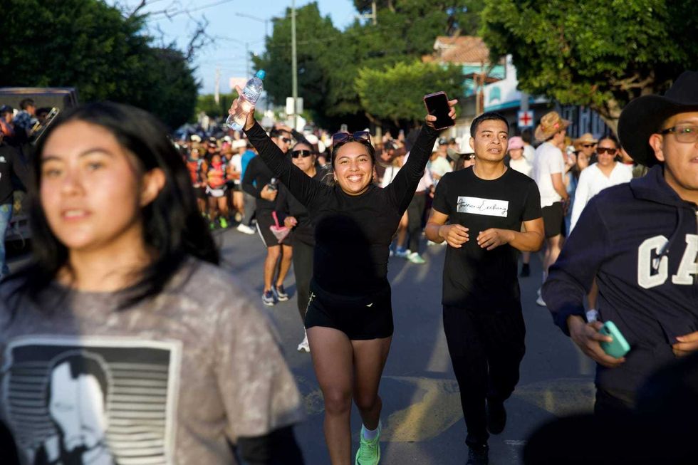 Corredora sonriente celebra con los brazos en alto durante la carrera FestiVaqueRun 2026 en San Juan del R\u00edo, Quer\u00e9taro