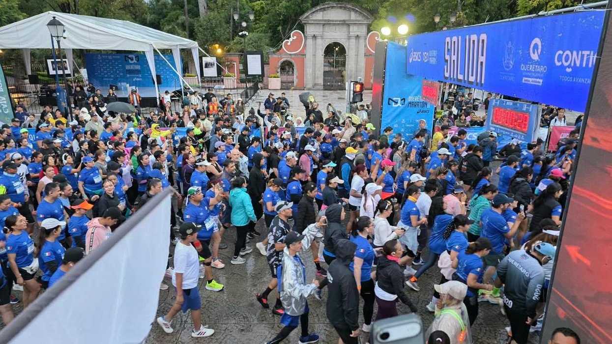Corredores y público frente al arco de salida del Querétaro Maratón 2026, con reloj de cronometraje a la derecha