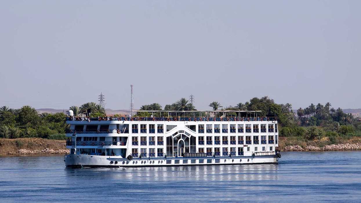 Crucero fluvial navegando el río Nilo en Egipto, rodeado de palmeras en la orilla.