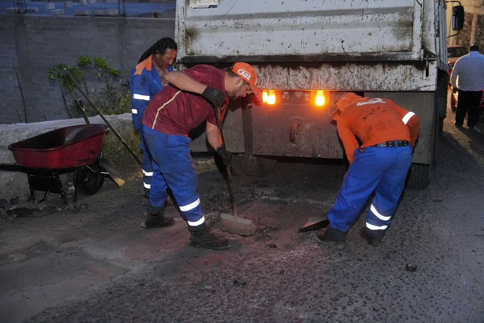 Cuadrilla municipal trabaja sobre bache con pala y pipa de asfalto al anochecer en Quer\u00e9taro