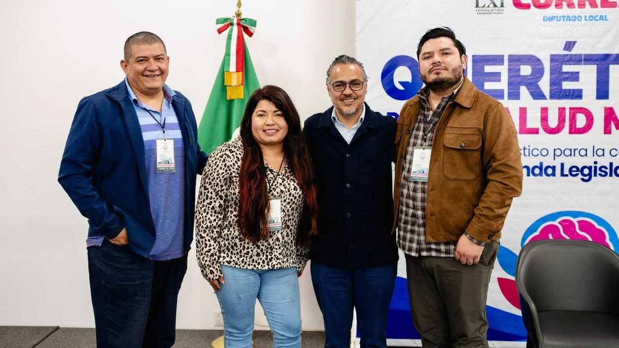 Cuatro asistentes con gafete posan frente a la bandera de México y la lona del foro Querétaro por la Salud Mental