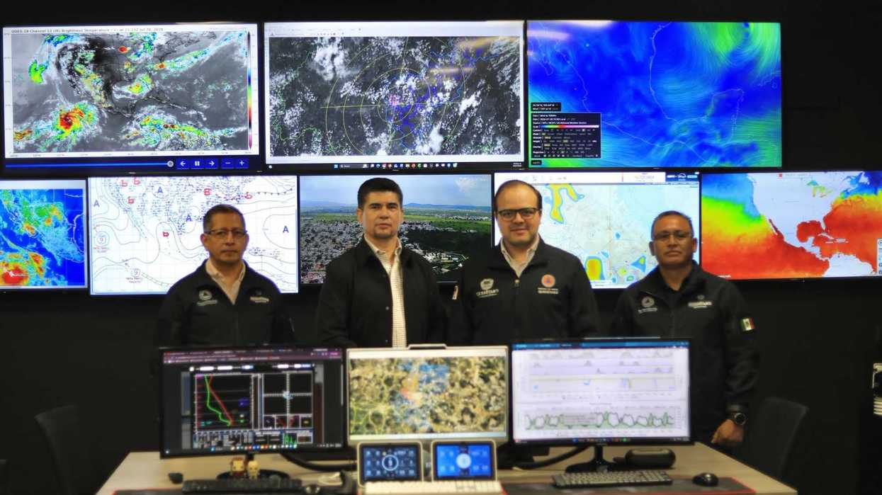 Cuatro funcionarios de Protección Civil de Querétaro posan frente a pantallas con mapas satelitales y datos meteorológicos en el centro de monitoreo climático.
