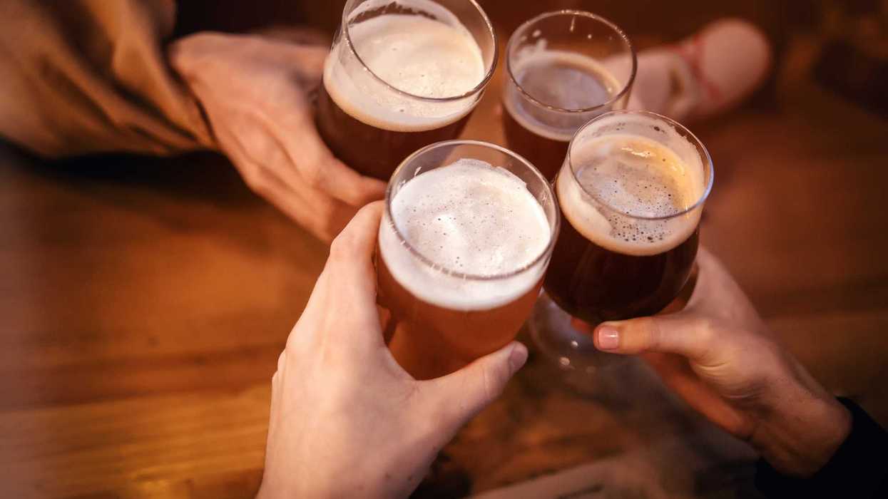 Cuatro manos brindan con vasos de cerveza artesanal sobre una mesa de madera; imagen ilustrativa del Bajío Beer Fest