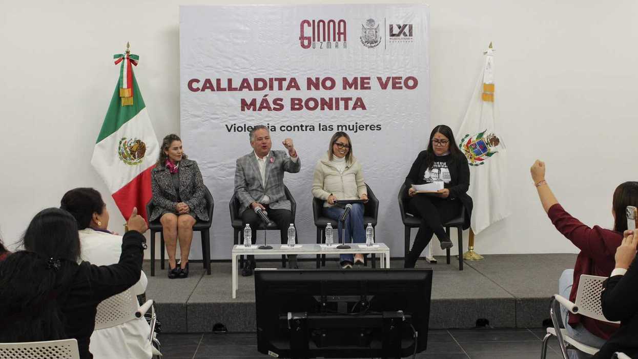 Cuatro personas sentadas en el panel del conversatorio frente a una lona con el título del evento