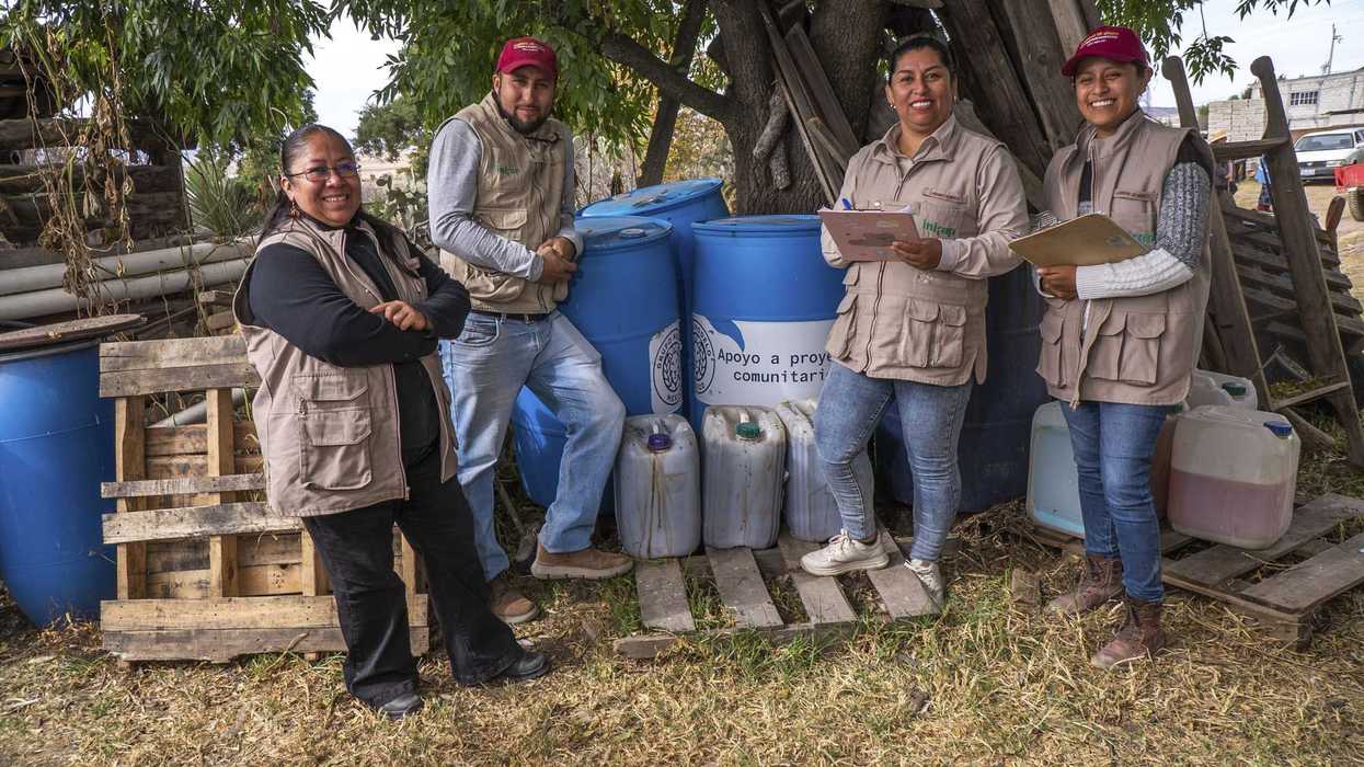 Cuatro técnicos de Agricultura e INIFAP posan junto a tambos identificados como apoyo a proyectos comunitarios