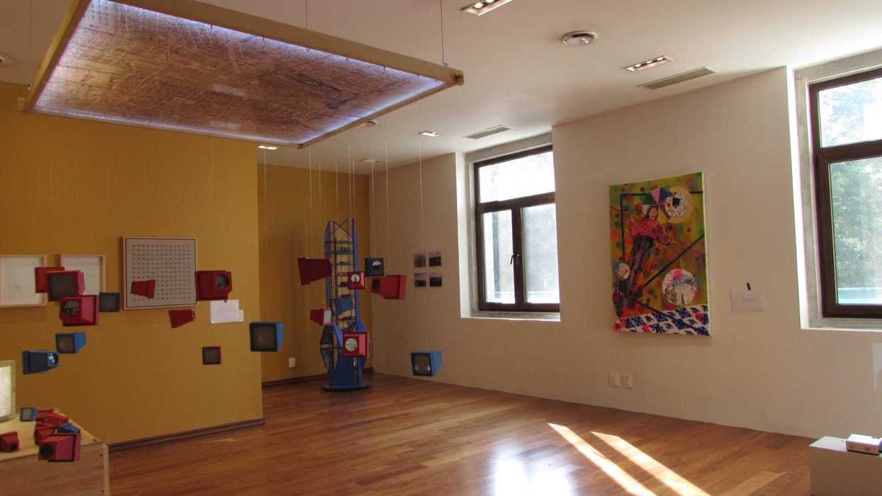 de exposición con instalación artística azul y roja, obras en pared y piso de madera, Jóvenes Creadores 2026
