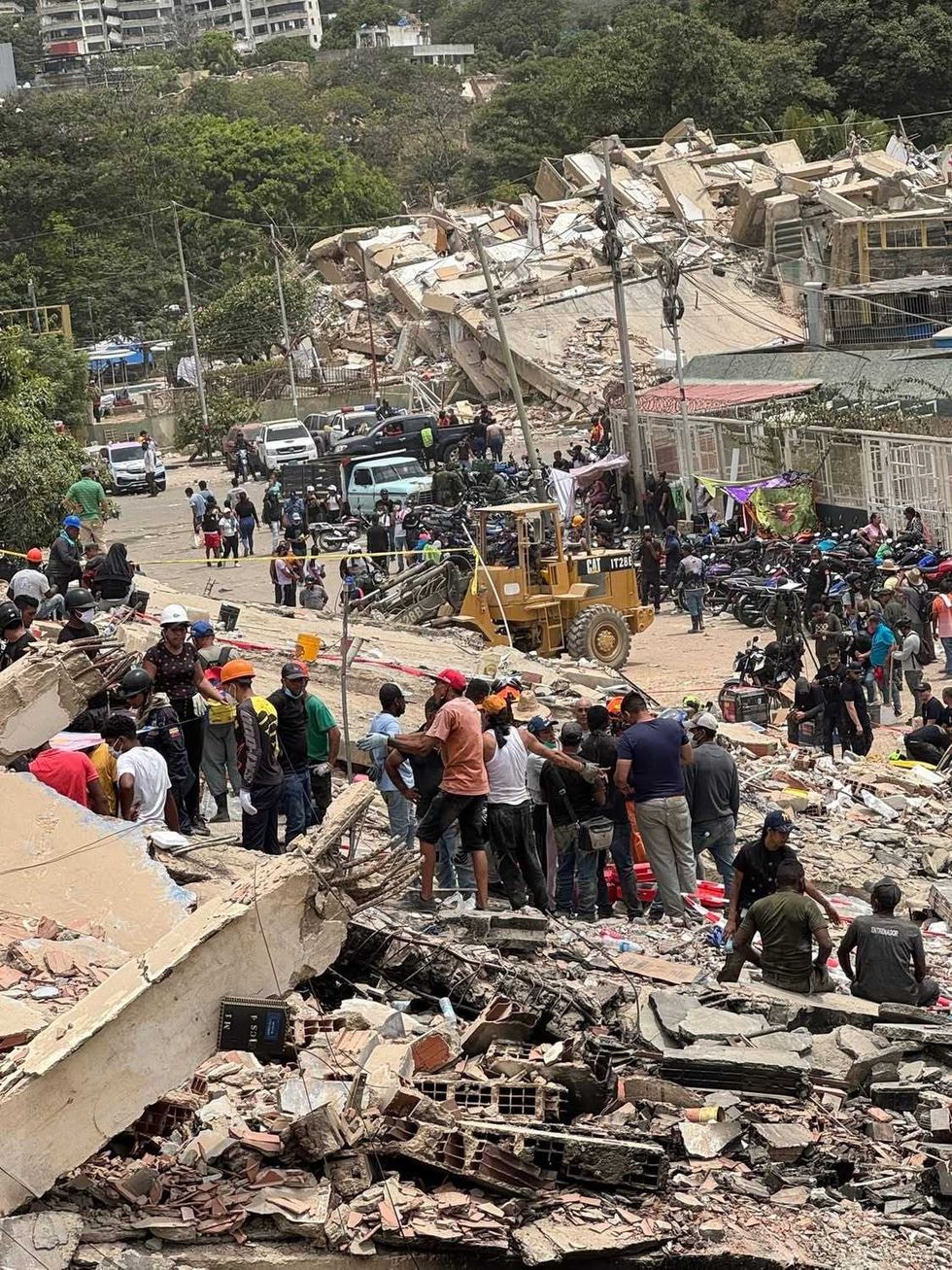 Decenas de personas y rescatistas remueven escombros de un edificio colapsado en La Guaira.