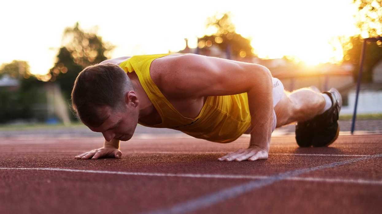 Deportista realiza flexiones en pista de atletismo al atardecer durante entrenamiento de alto rendimiento