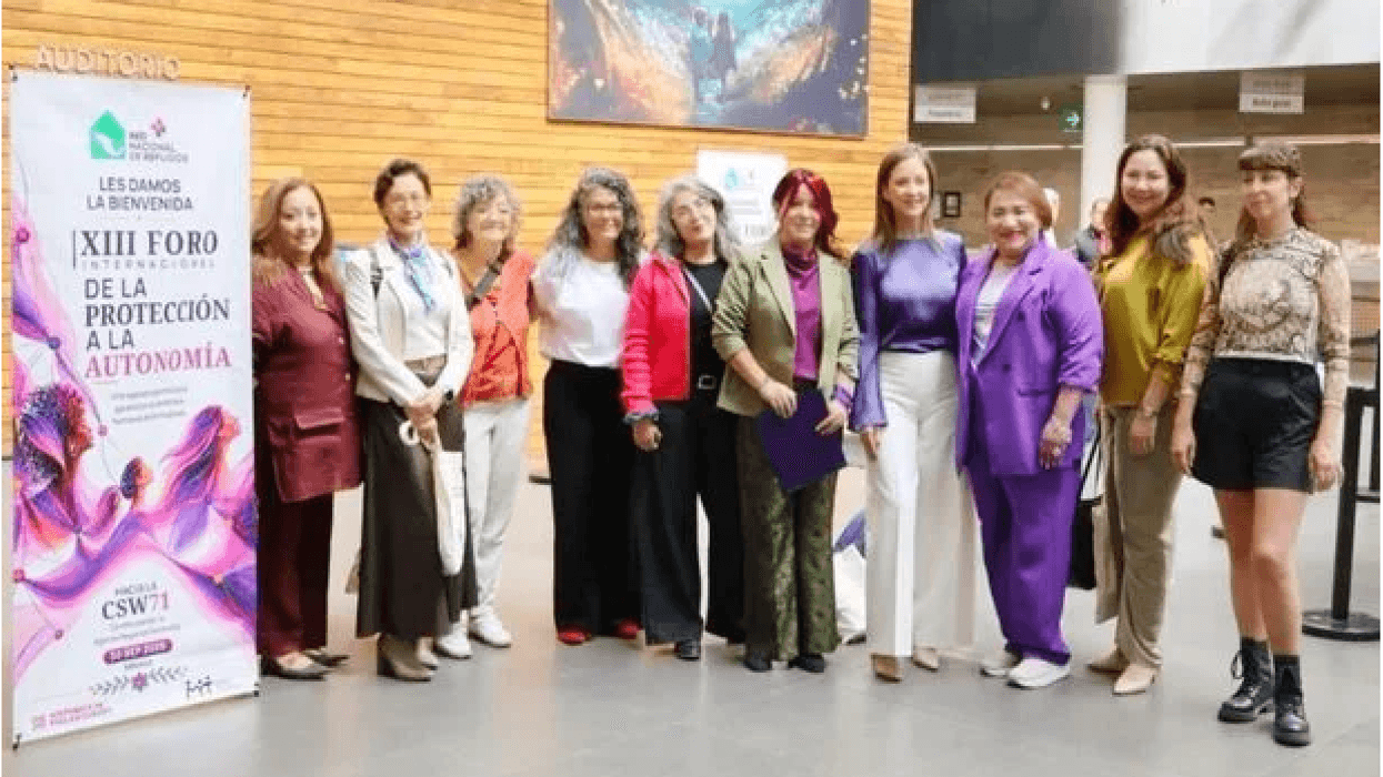 Diez participantes del XIII Foro Internacional de la Red Nacional de Refugios posan junto al cartel del encuentro