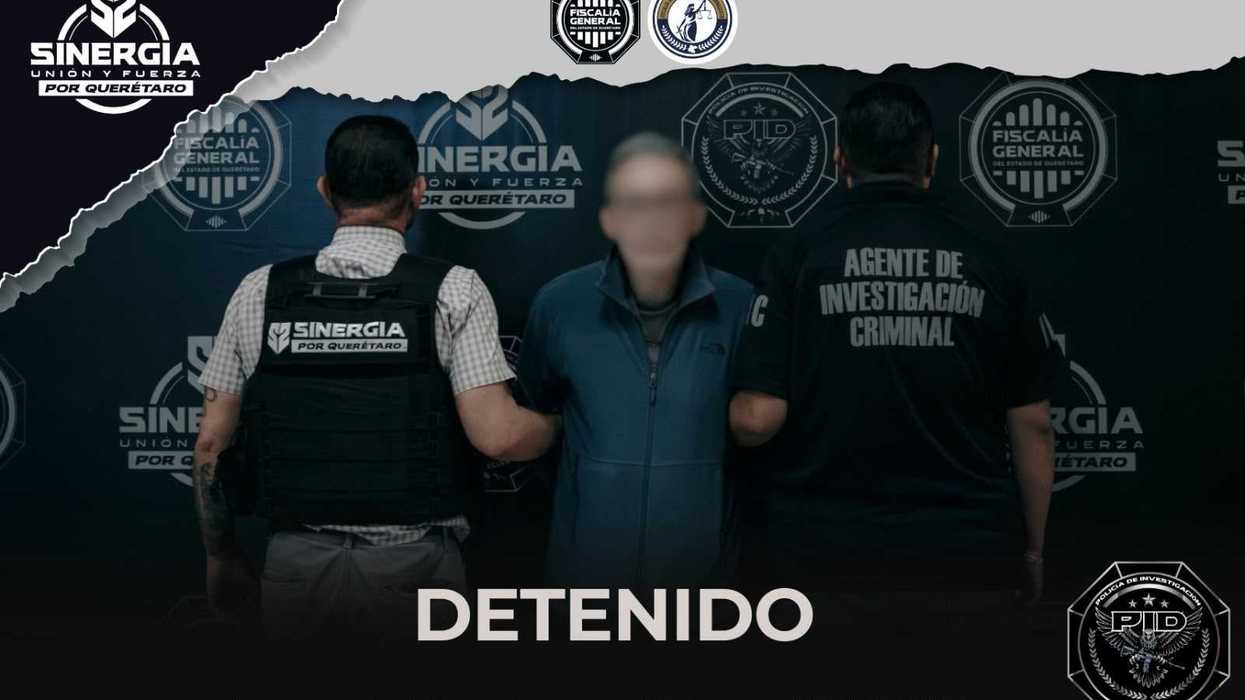 Dos agentes de investigación sujetan de los brazos a un hombre con el rostro difuminado, médico detenido en Corregidora, ante un fondo con logotipos de Sinergia por Querétaro y de la Fiscalía.