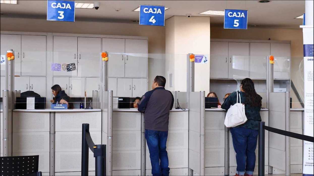 Dos contribuyentes esperan atención frente a las cajas 3, 4 y 5 de una oficina municipal de Querétaro, en el contexto del descuento en predial.
