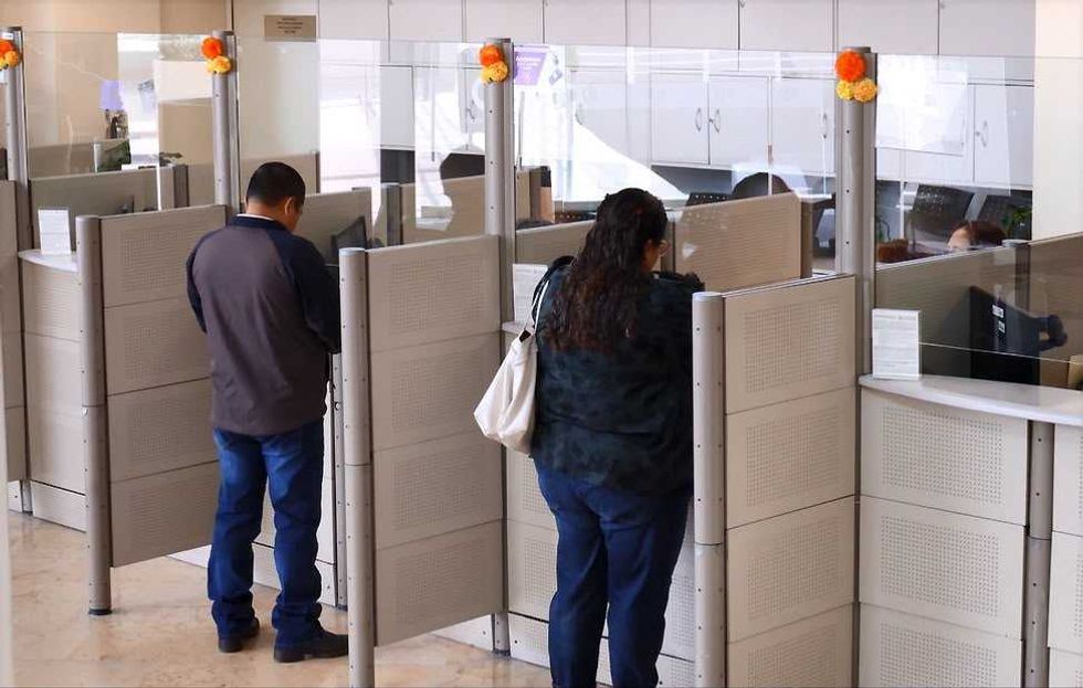 Dos contribuyentes realizan tr\u00e1mites de pie en m\u00f3dulos de atenci\u00f3n del Municipio de Quer\u00e9taro, en el contexto del descuento en predial de octubre.