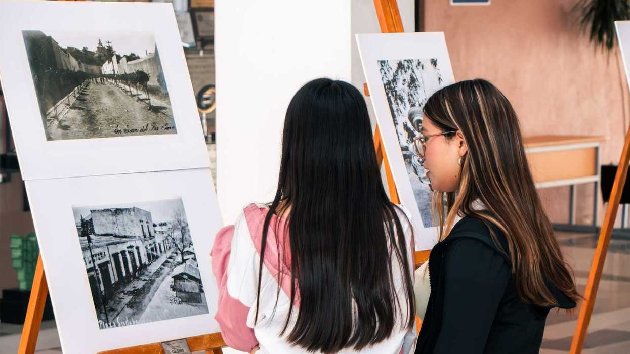 Dos estudiantes observan fotografías antiguas de San Juan del Río en la exposición "La Ciudad".