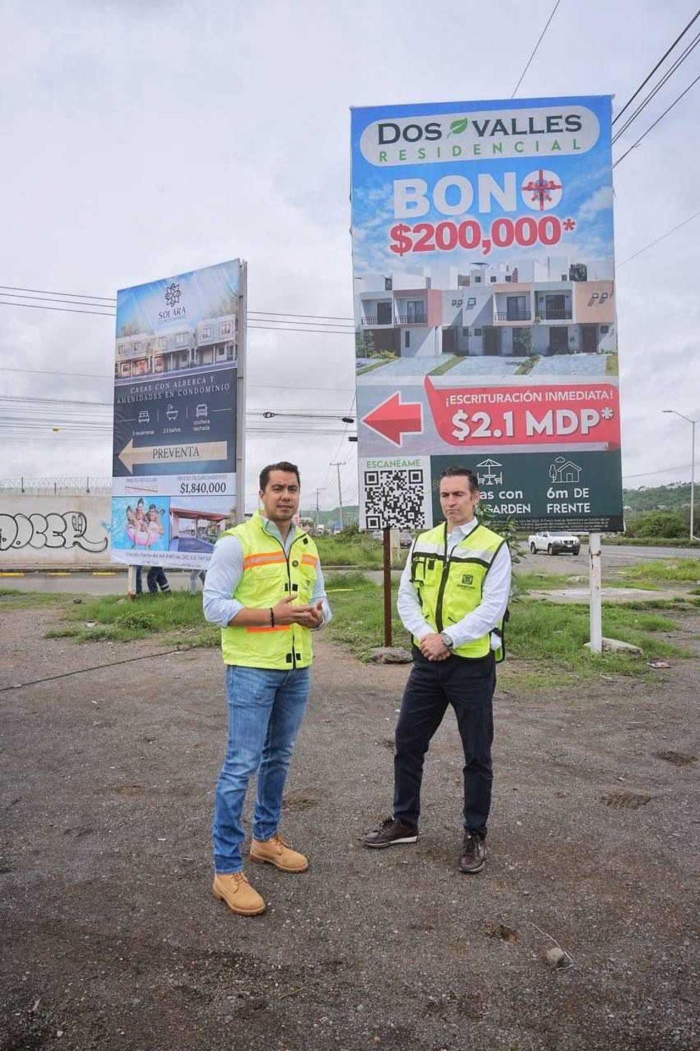 Dos funcionarios con chalecos de Plan Orden frente a espectaculares de los desarrollos Solara y Dos Valles Residencial en Quer\u00e9taro