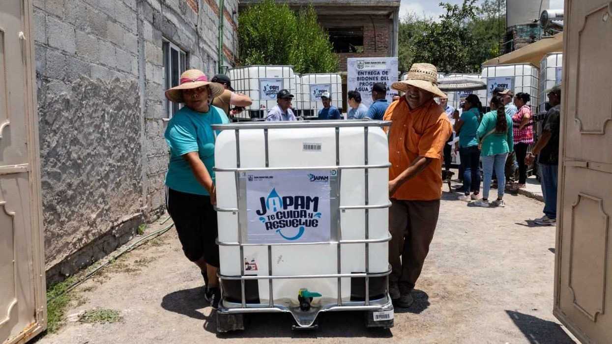 Dos habitantes de La Llave desplazan un contenedor de mil litros del programa Agua Segura de JAPAM durante la entrega en San Juan del Río.