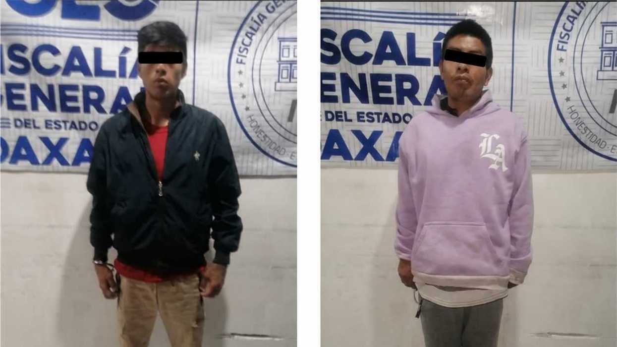 Dos hombres con el rostro cubierto, frente a una lona de la Fiscalía General del Estado de Oaxaca