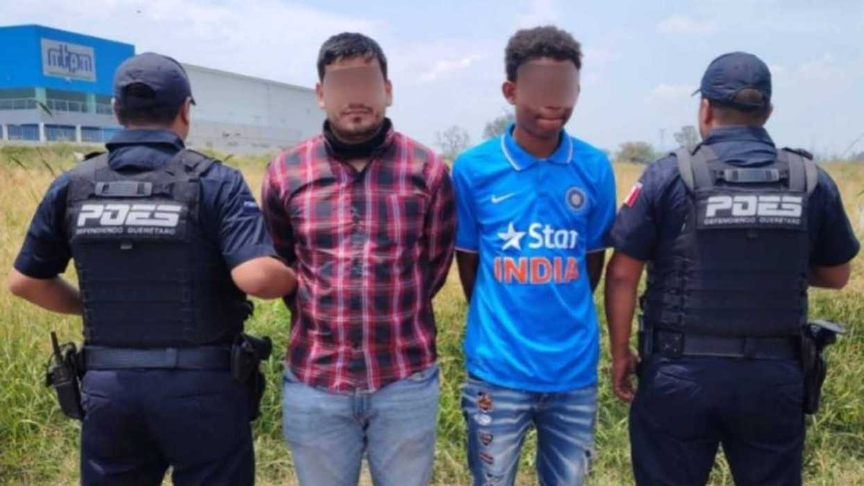 Dos hombres detenidos son custodiados por policías estatales en Calamanda, municipio de El Marqués, Querétaro.