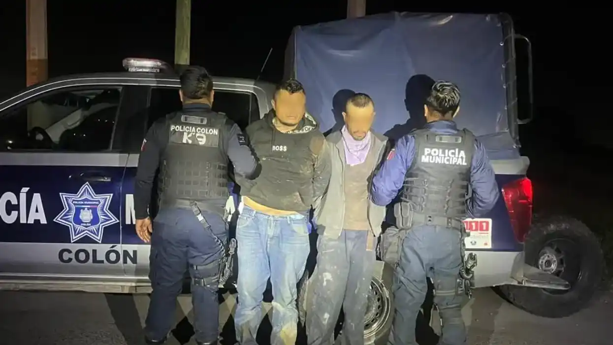 Dos hombres permanecen bajo custodia de policías municipales de Colón frente a una patrulla durante un operativo nocturno.