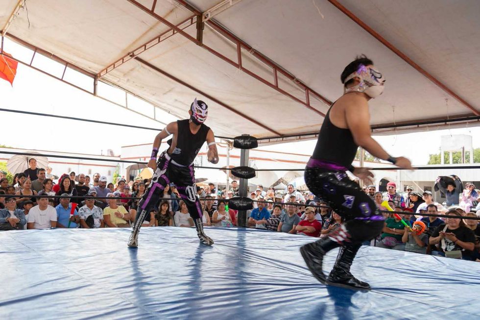 Dos luchadores se desplazan sobre el ring ante el p\u00fablico sentado durante la funci\u00f3n de lucha libre del Paseo Dominical en la Ex Hacienda La Llave.