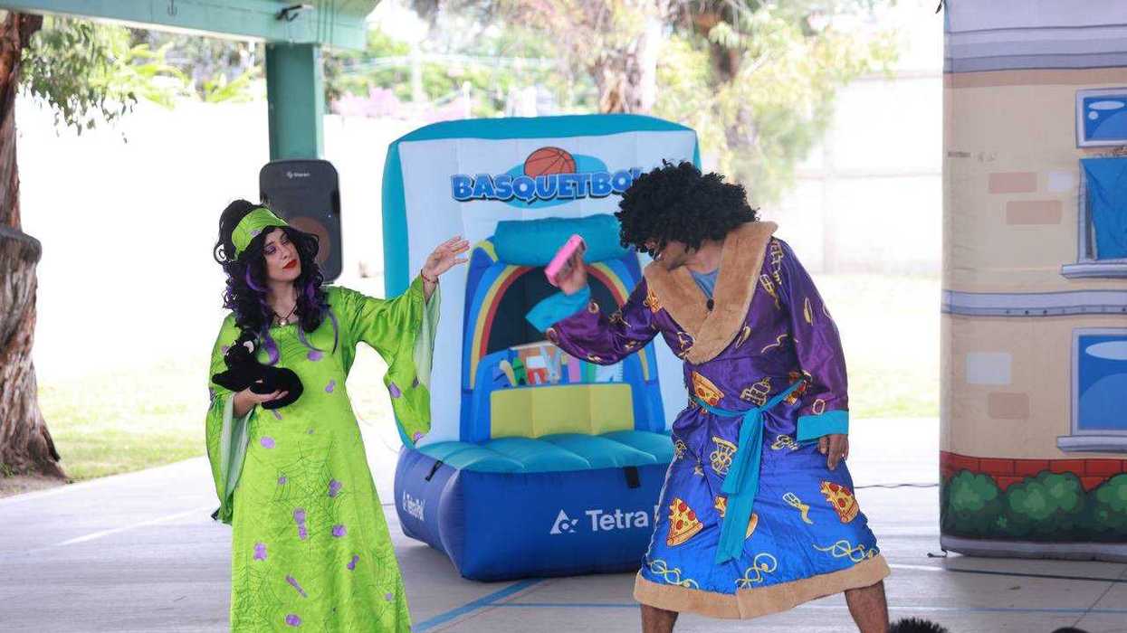 Dos personajes caracterizados actúan junto a un módulo inflable de basquetbol durante la obra de teatro Ponte Pilas en una escuela de Corregidora.
