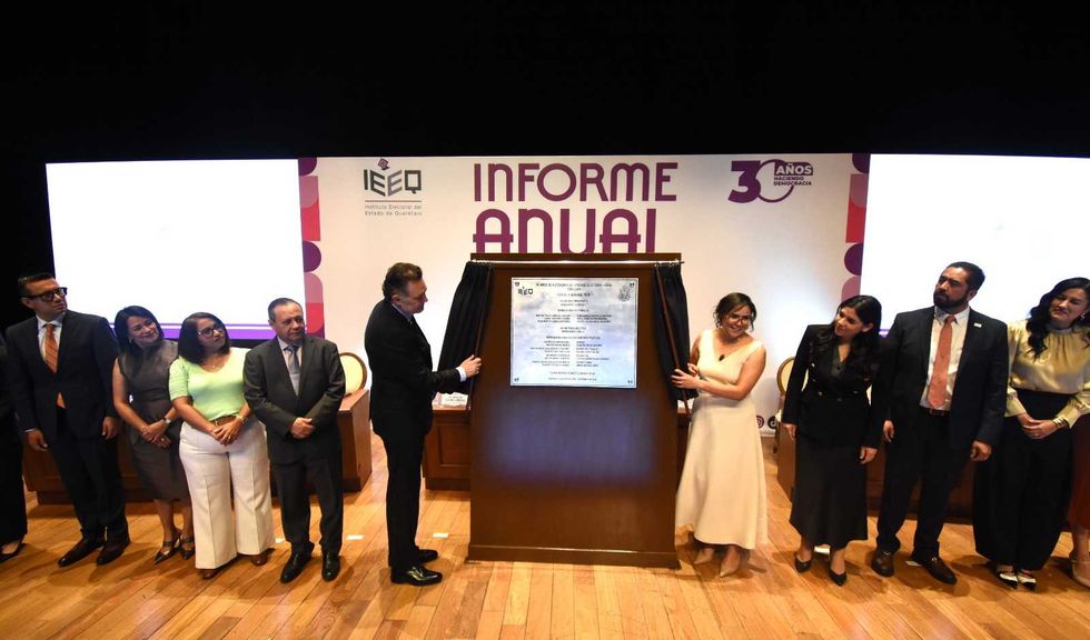 Dos personas descubren la placa conmemorativa por los 30 a\u00f1os de autonom\u00eda del IEEQ ante integrantes del pres\u00eddium