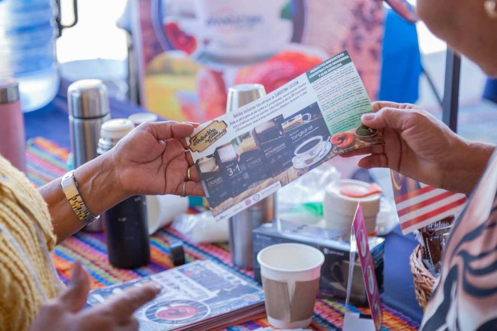 Dos personas revisan un folleto de bebidas de caf\u00e9 en un puesto del Festival del Caf\u00e9 en San Juan del R\u00edo.