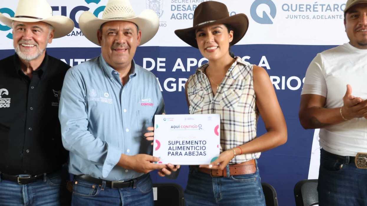 Dos personas sostienen una placa de Suplemento alimenticio para abejas durante la entrega de apoyo de la SEDEA a apicultores