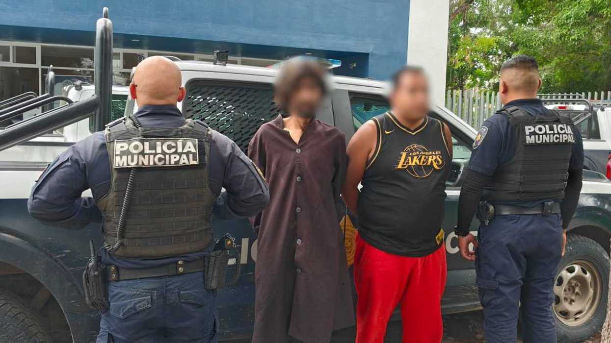 Dos policías municipales custodian a dos detenidos con rostro cubierto junto a una patrulla en Pinto, Querétaro