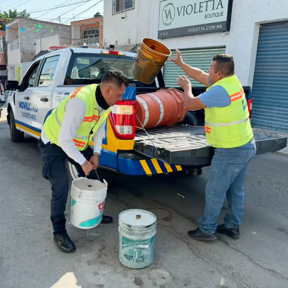Dos trabajadores con chalecos del Plan Orden suben cubetas y un trafitambo a una camioneta de Movilidad