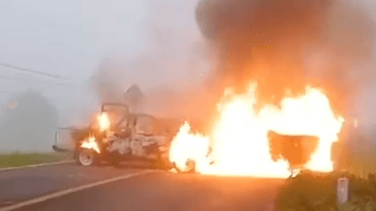 Dos vehículos en llamas sobre carretera bloqueada en Michoacán durante narcobloqueos del 19 de agosto de 2026.