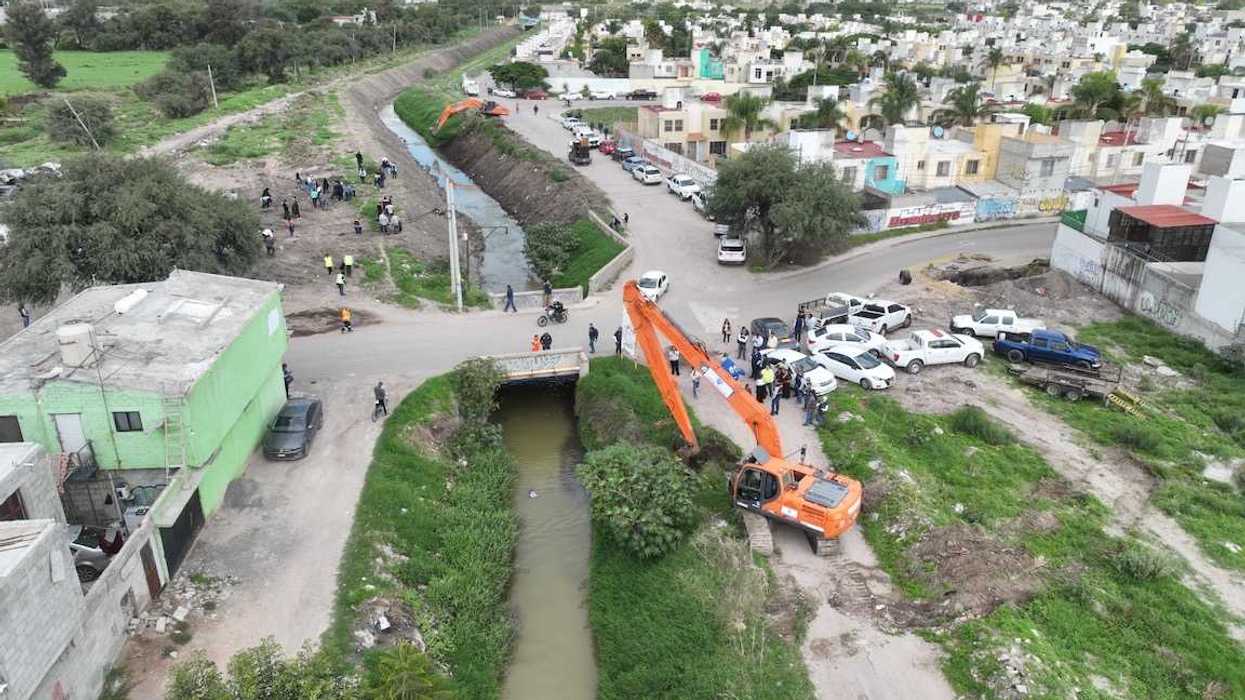 Draga naranja de brazo largo opera sobre el cauce del río Querétaro en Santa María Magdalena mientras personal técnico supervisa los trabajos