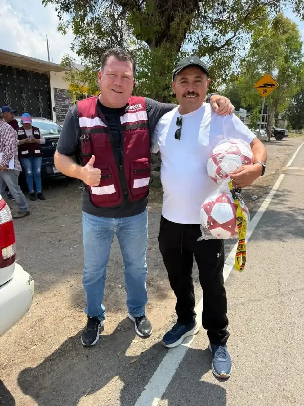 Edgar Inzunza junto a un hombre que sostiene dos balones de futbol