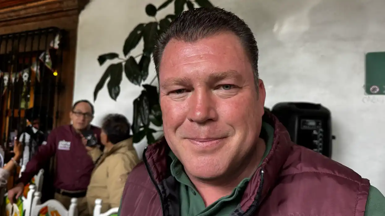 Edgar Inzunza, sentado, gesticula mientras conversa en un espacio interior con luz natural