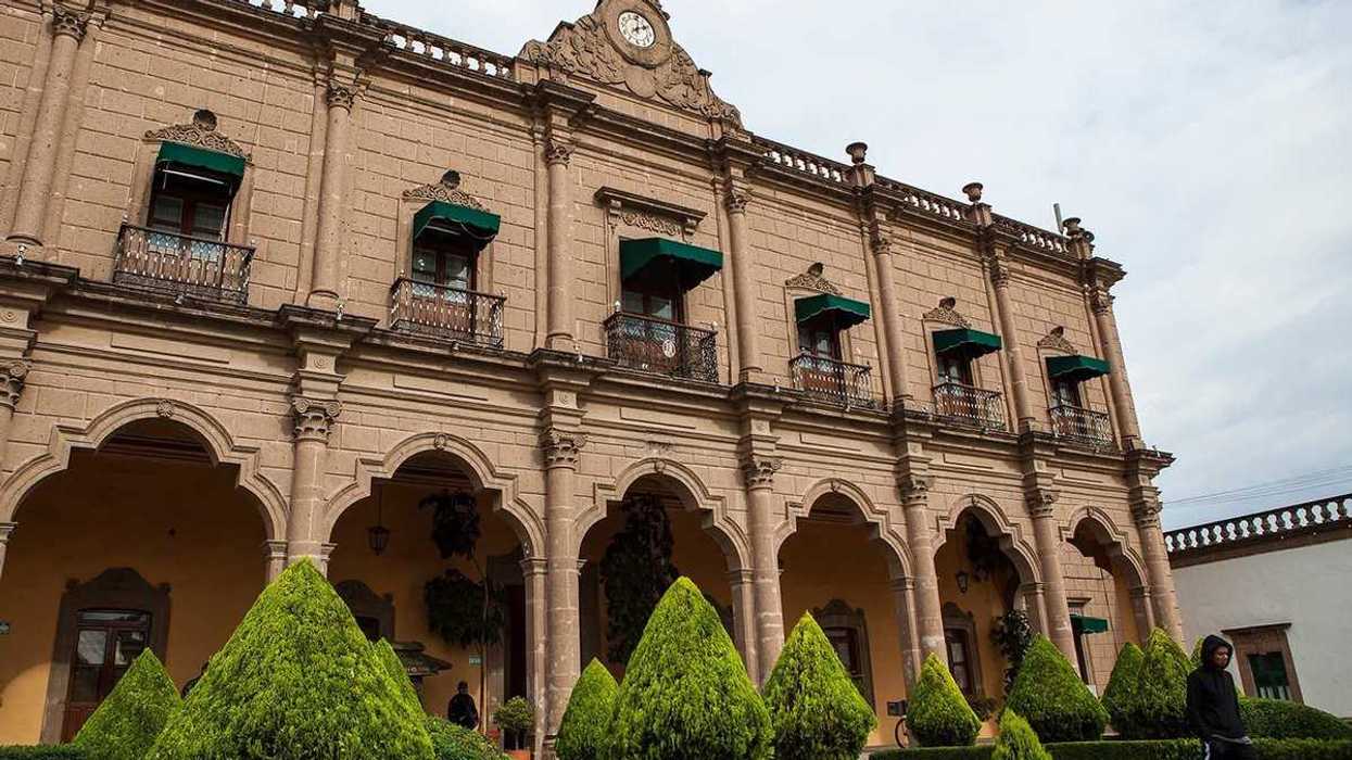Edificio de cantera de dos niveles con arcos y reloj en el centro de Huichapan