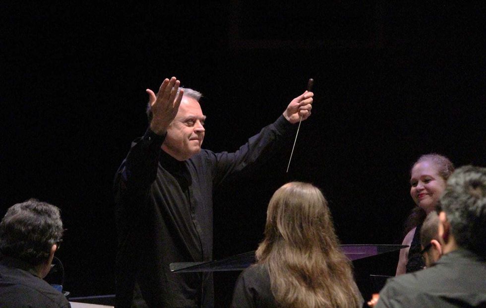 El director de la orquesta hace una reverencia con la batuta en alto ante el p\u00fablico tras una presentaci\u00f3n.