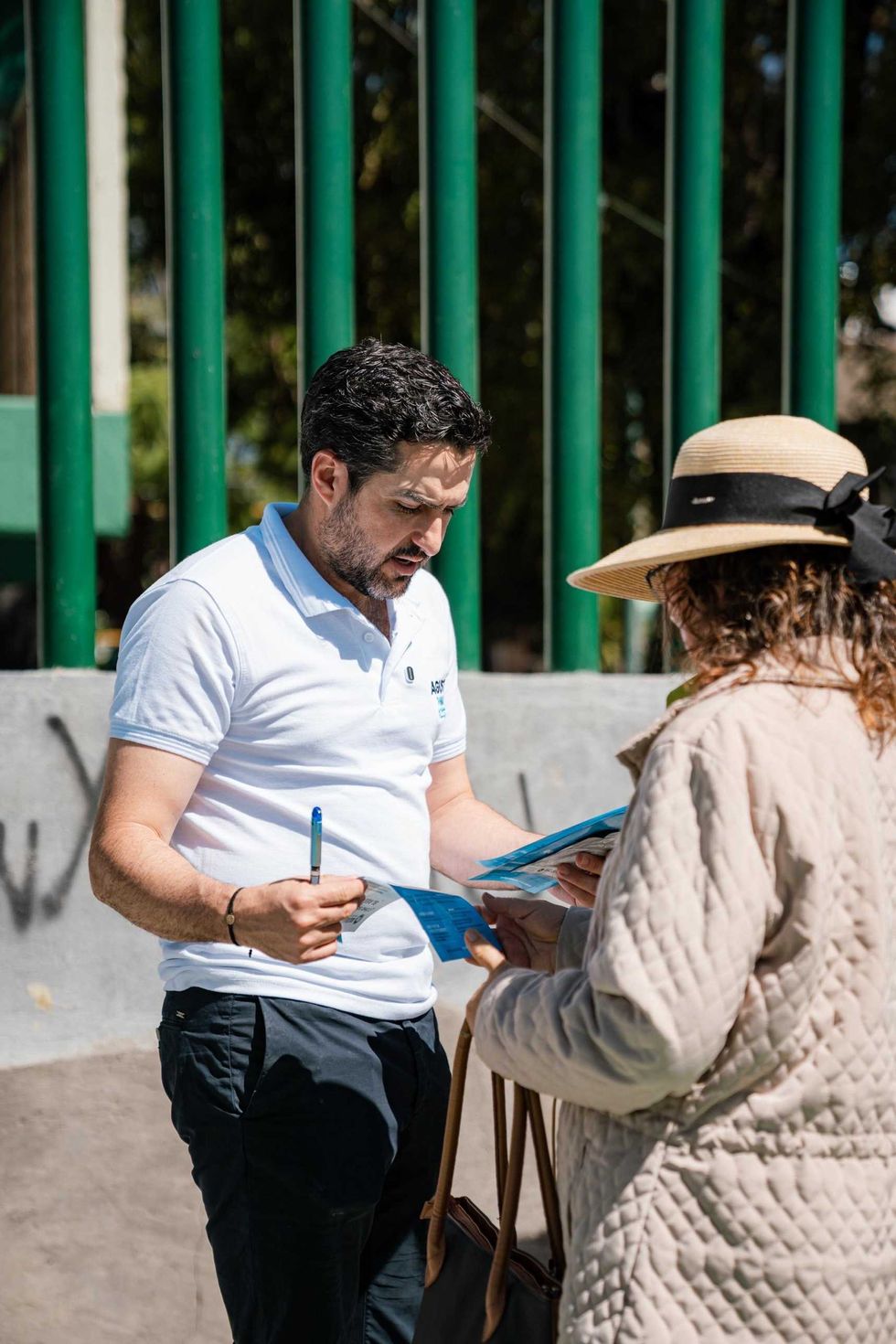 El senador Agust\u00edn Dorantes L\u00e1mbarri, con playera blanca, habla con un grupo de personas reunidas en un espacio p\u00fablico con reja y \u00e1rboles al fondo; imagen ligada a la iniciativa ciudadana Ley Reembolso.