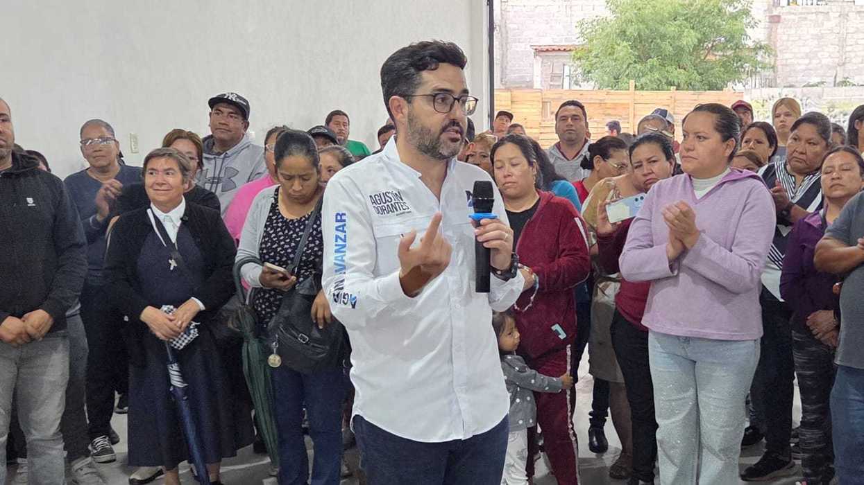 El senador Agustín Dorantes habla con micrófono ante vecinos de Colinas de Menchaca en una reunión por regularización.