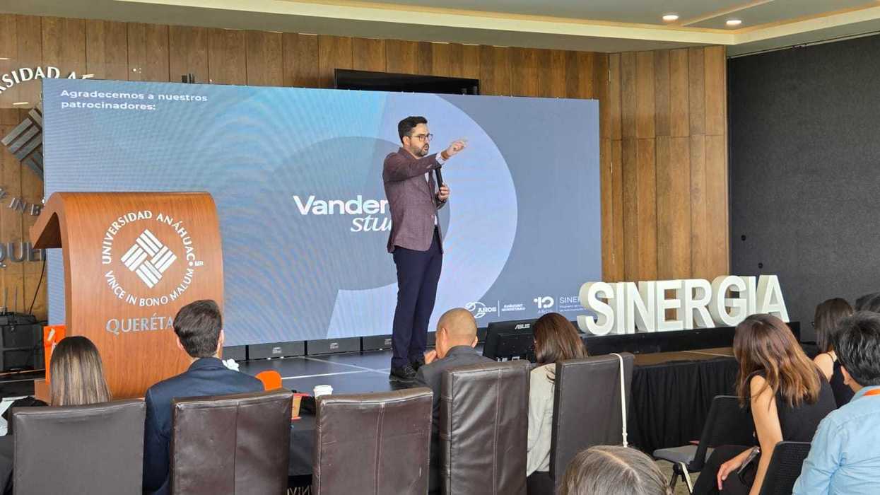 El senador Agustín Dorantes Lámbarri habla en el escenario del Concurso de Oratoria 10 años de Sinergia, junto al letrero SINERGIA, en Querétaro.