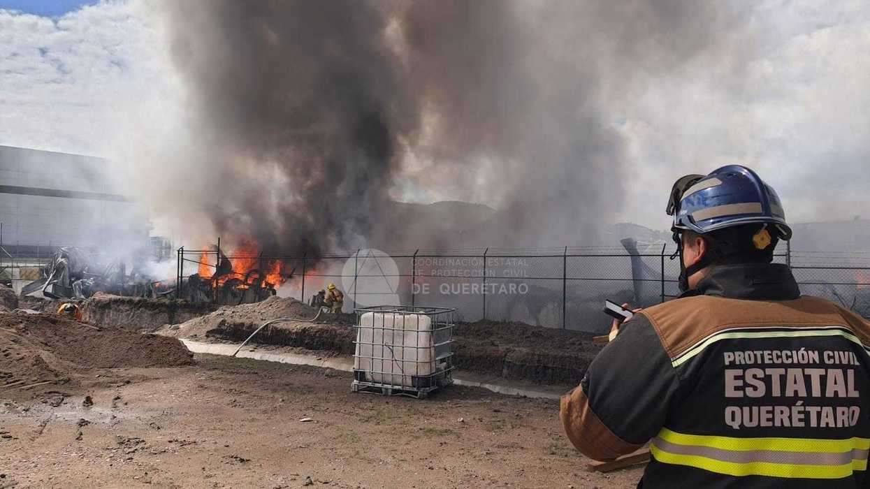 Elemento de Protección Civil Estatal observa el incendio de una fábrica de tarimas de plástico en el Parque Industrial Querétaro.