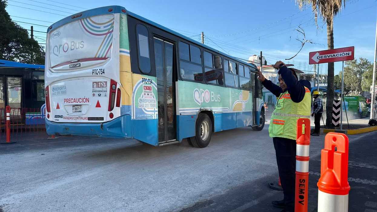 Elemento de tránsito guía el paso de un autobús Qrobus junto a un señalamiento de desviación