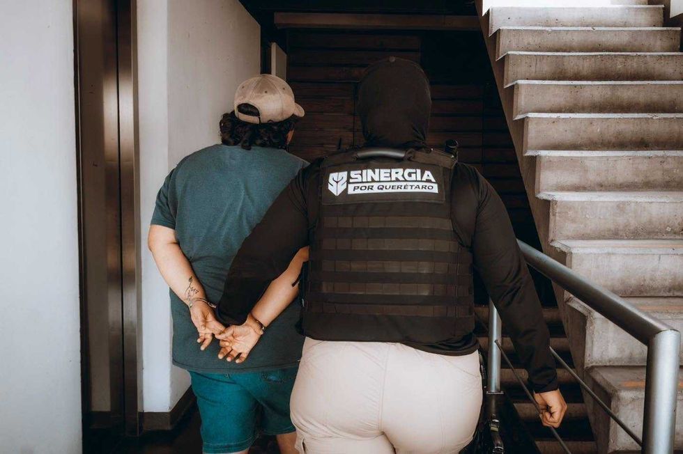 Elemento del operativo Sinergia acompa\u00f1a a una persona detenida durante las diligencias realizadas en Quer\u00e9taro.