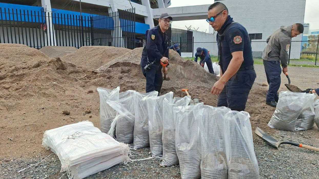 Elementos de Bomberos y Protección Civil llenan costales de arena junto a un montículo frente al Estadio Corregidora