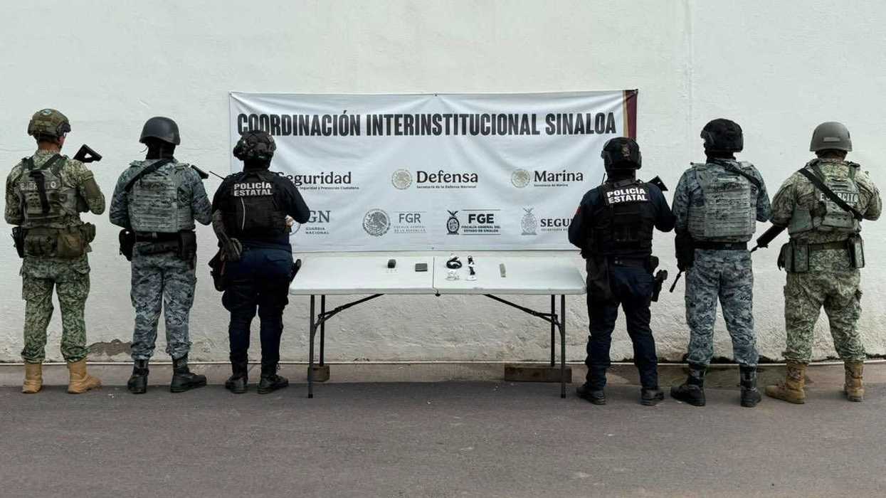 Elementos de fuerzas de seguridad de espaldas frente a mesa con objetos asegurados y manta de la Coordinación Interinstitucional Sinaloa