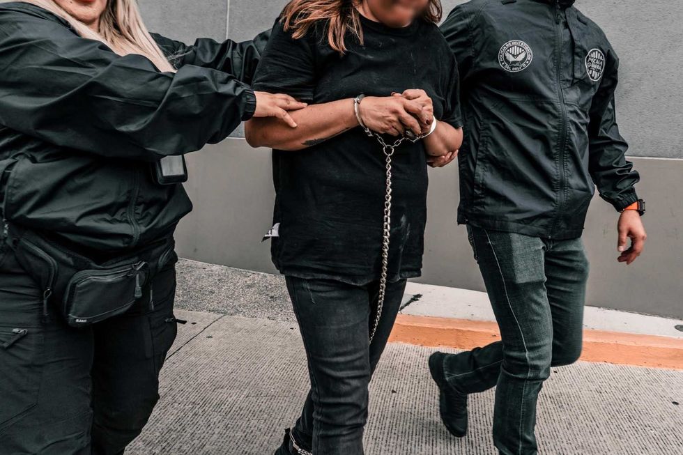 Elementos de la Polic\u00eda de Investigaci\u00f3n del Delito trasladan caminando a una persona detenida hacia un veh\u00edculo oficial.