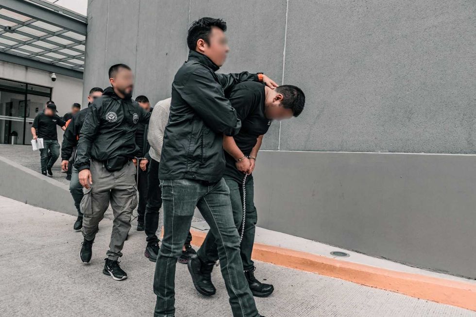 Elementos de la Polic\u00eda de Investigaci\u00f3n del Delito trasladan caminando a una persona detenida hacia un veh\u00edculo oficial.